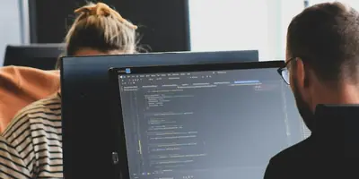 Developers working at office monitors with source code visible on a screen